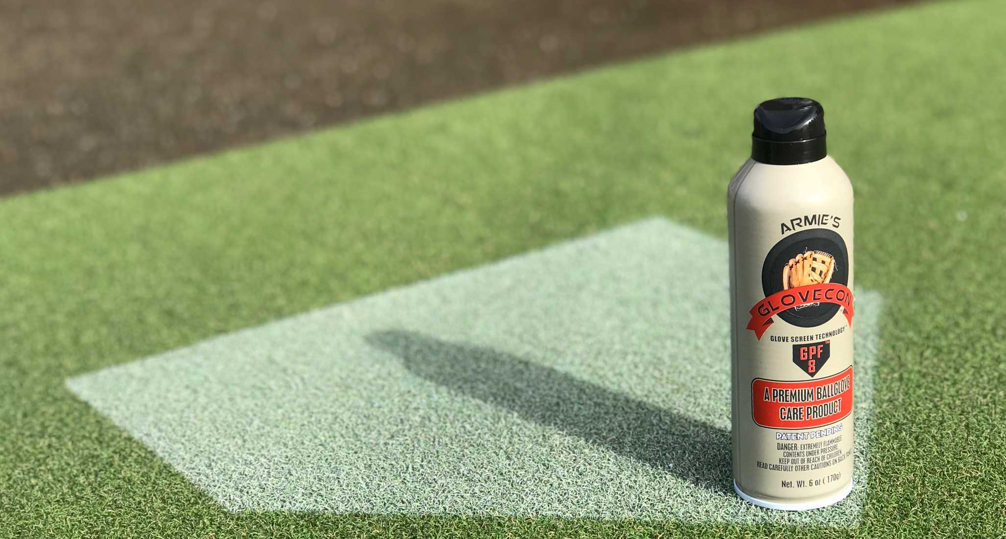 GloveCon Aerosol spray can solo product image sitting on home plate with green turf